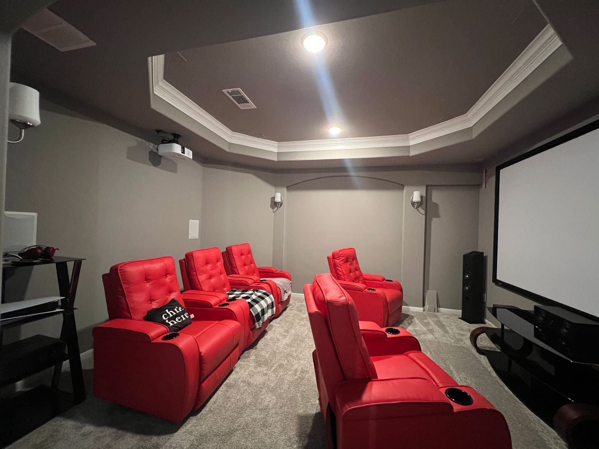 Home theater with red leather recliners and a tray ceiling