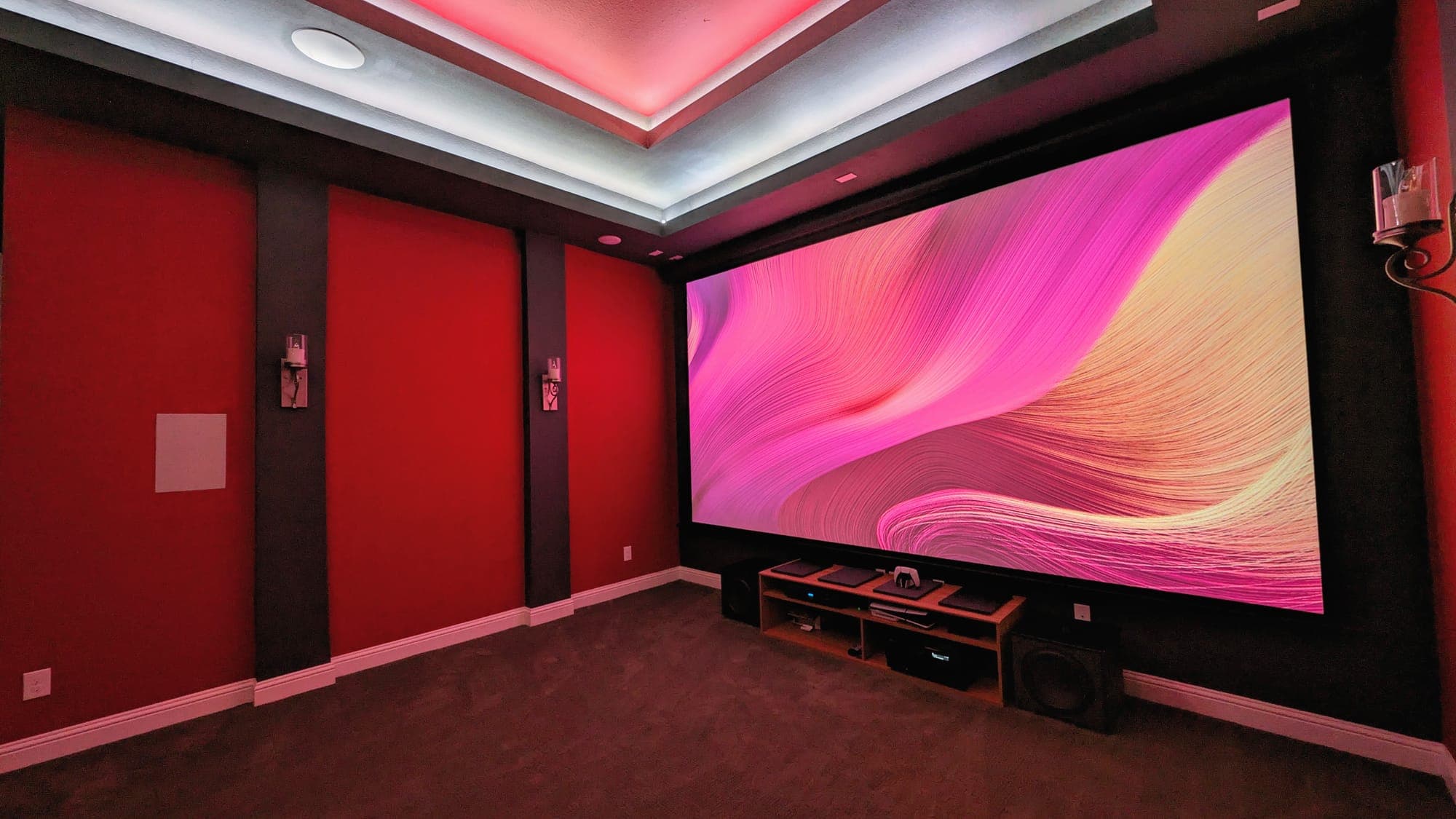 Home theater with red walls, cove lighting, and a large screen