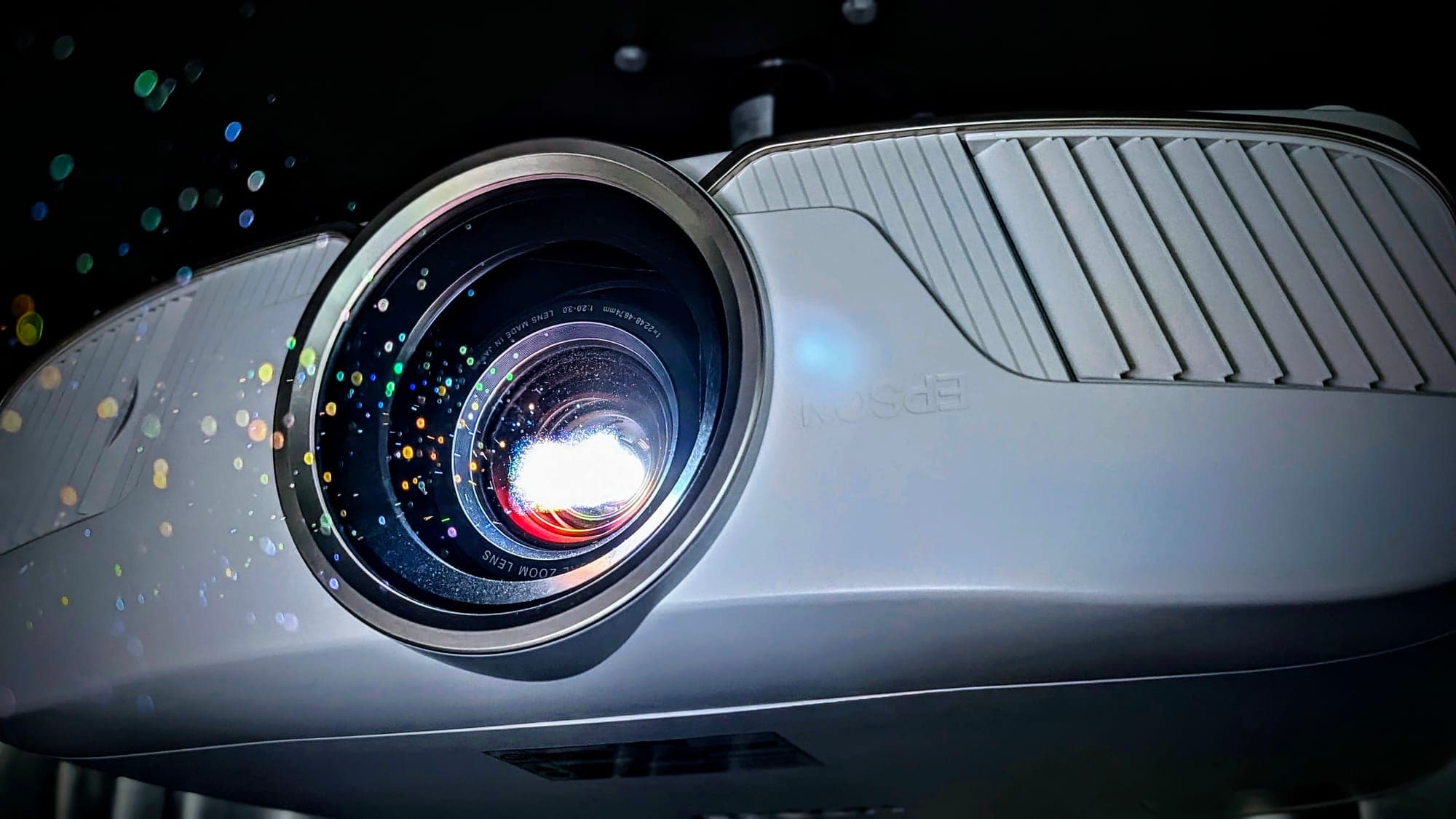 Close-up of a home theater projector lens against a dark background